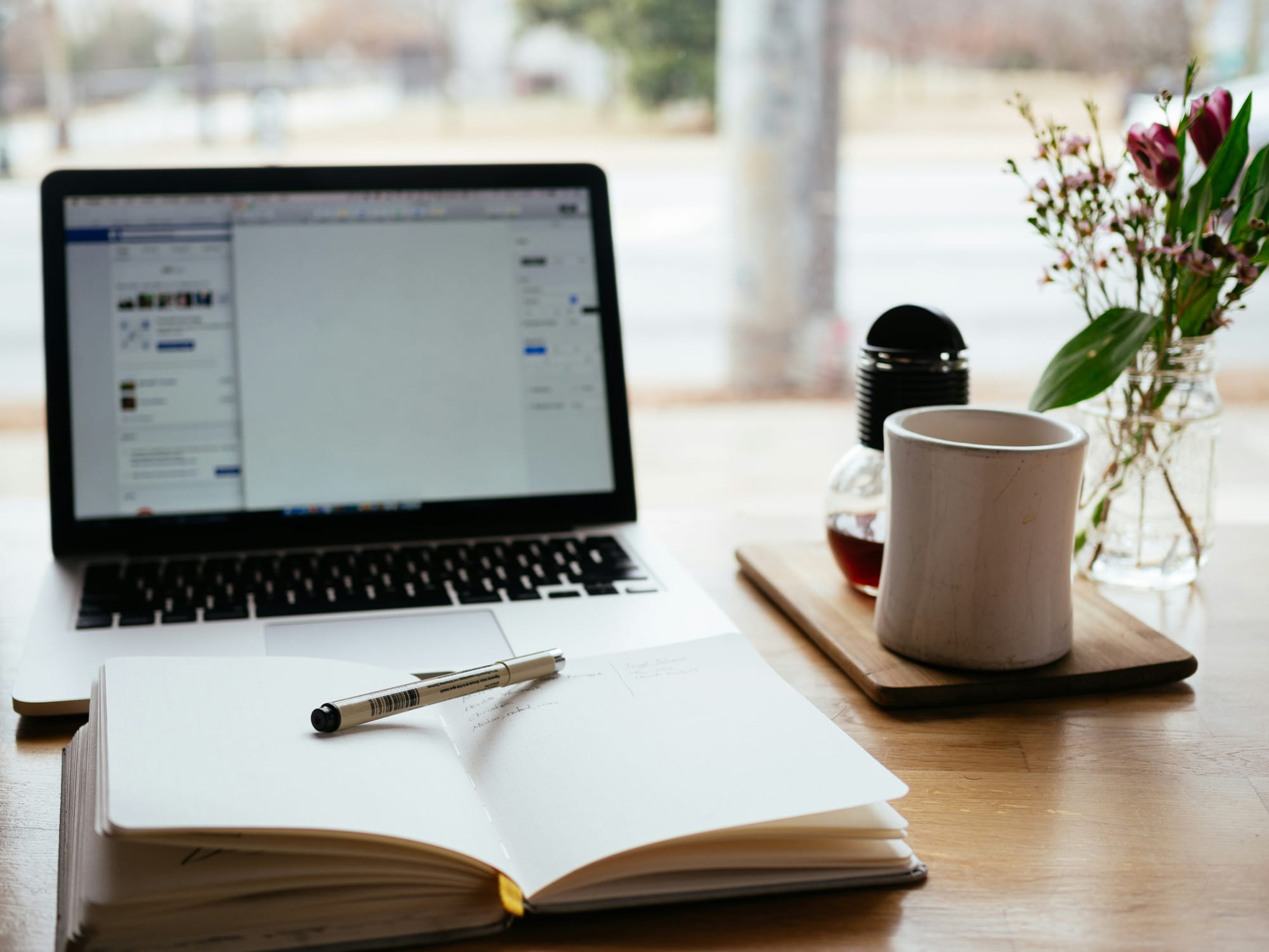 Laptop Opened in Front of the Book and Pencil Alongside the Cup – Content Automation Services